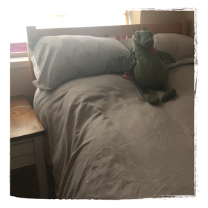 a bed with a dragon stuffed toy